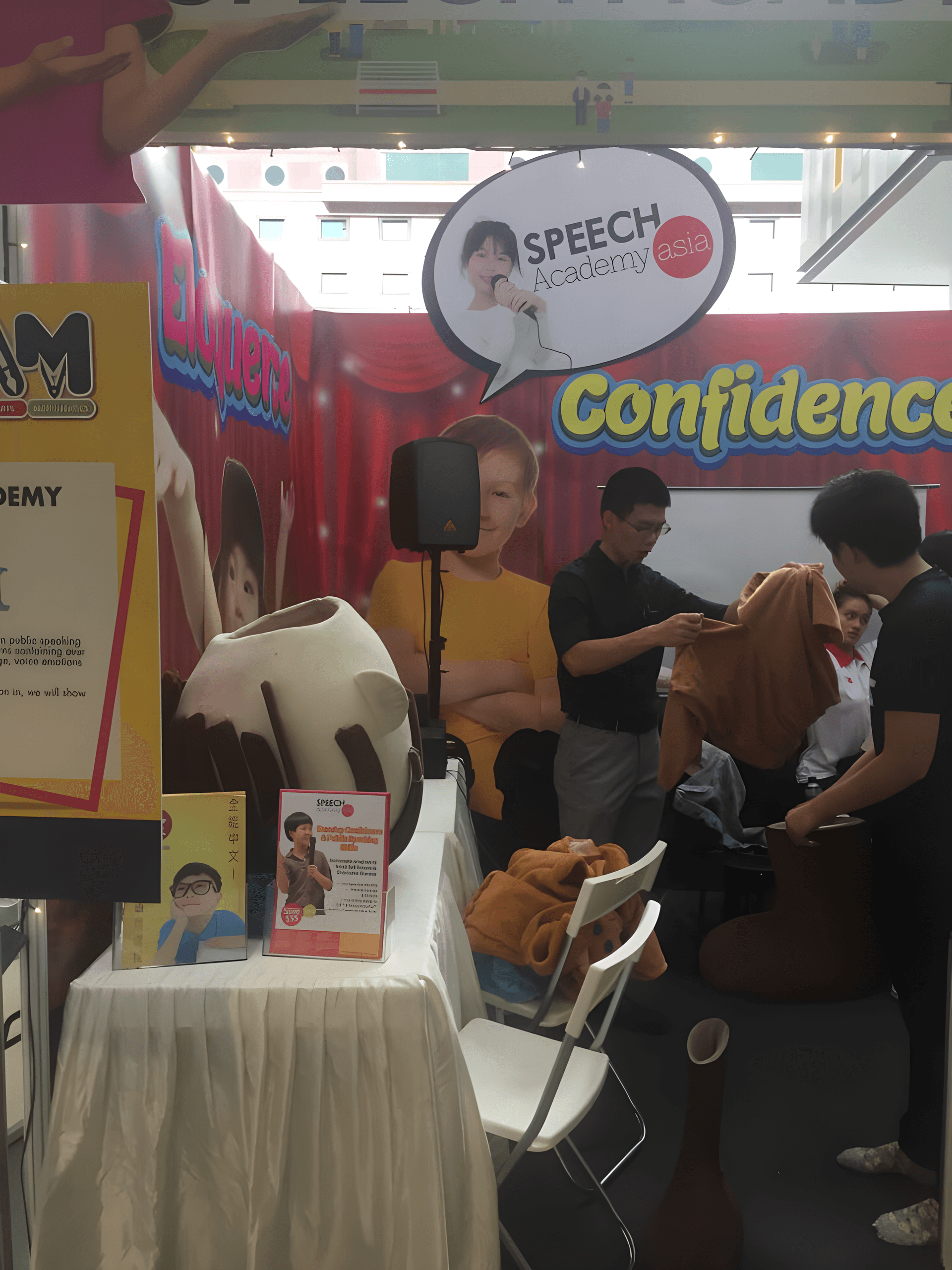 Compact PA speaker on a stand at a Speech Academy Asia roadshow booth — portable sound system rental