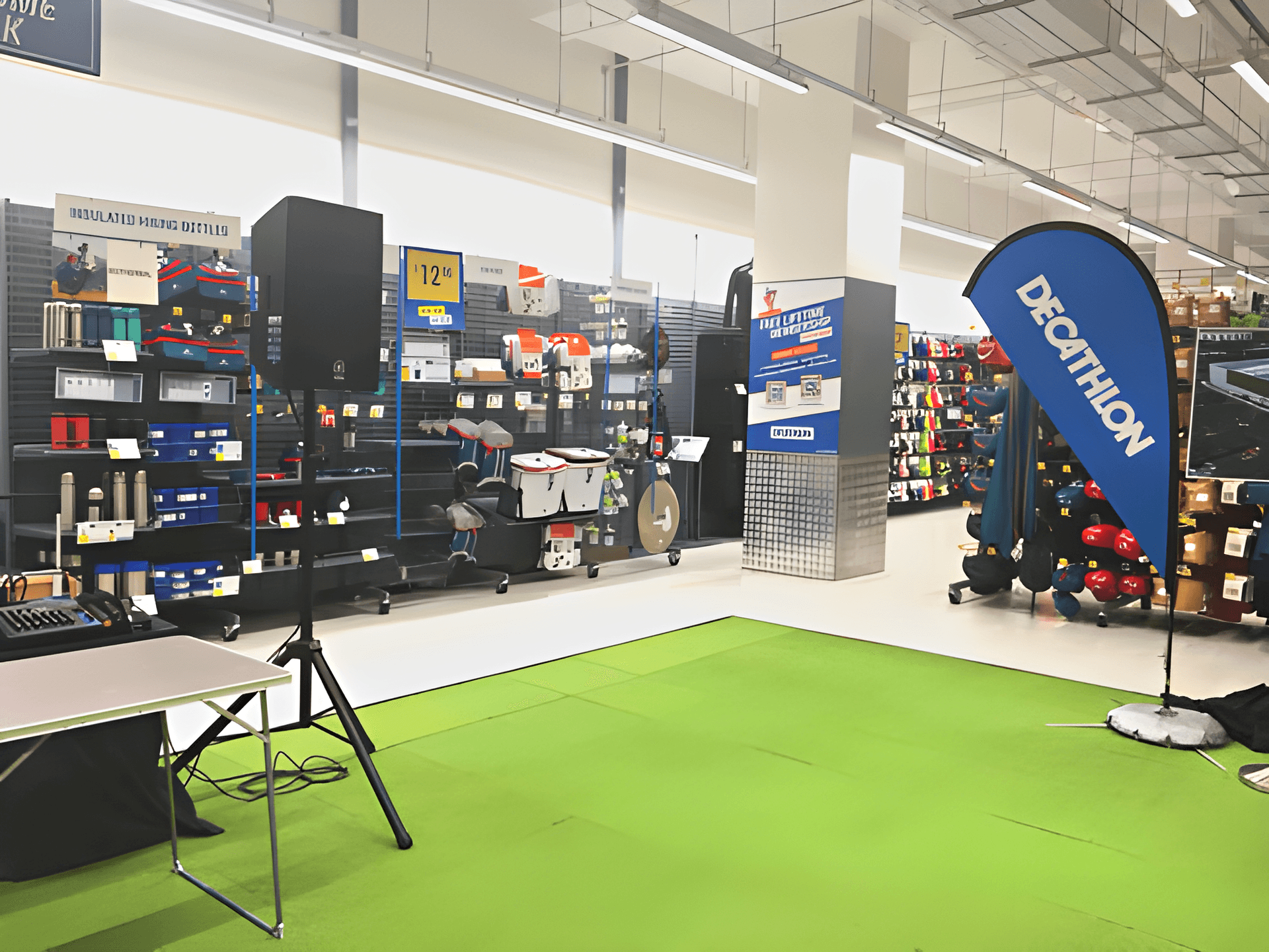 Powered PA speaker on a tripod stand with a mixer console at a Decathlon in-store event, Bedok event hall